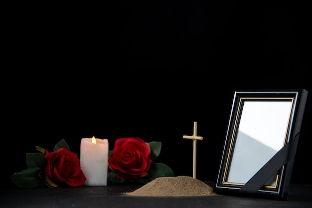 Вид спереди могилы со свечой и красными розами на черном