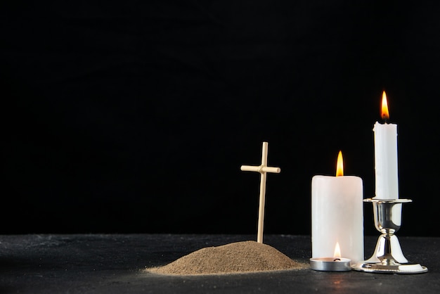 Vista frontale della piccola tomba con candele sul nero