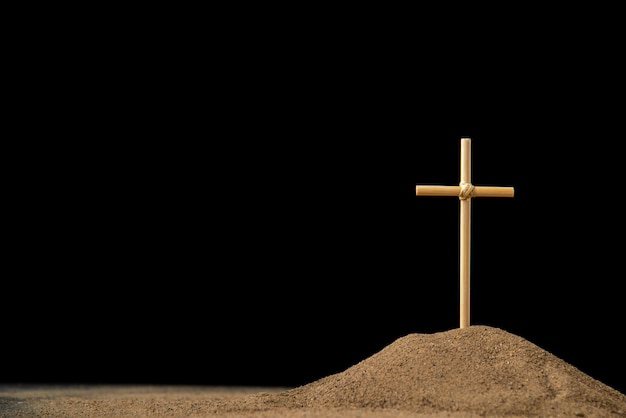 Front view of little grave with cross on dark