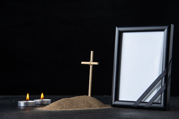 Front view of little grave with cross and picture frame on dark