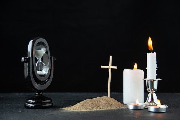 Free photo front view of little grave with hourglass and candles on dark