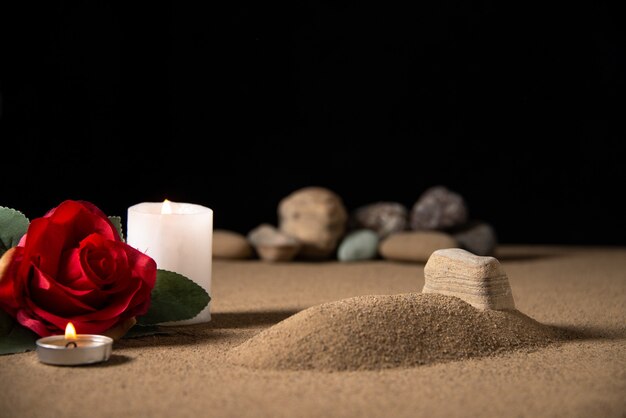 모래 장례식 죽음에 붉은 꽃과 촛불이있는 작은 무덤의 전면보기
