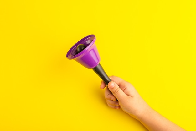 Front view little kid holding purple bell on yellow surface