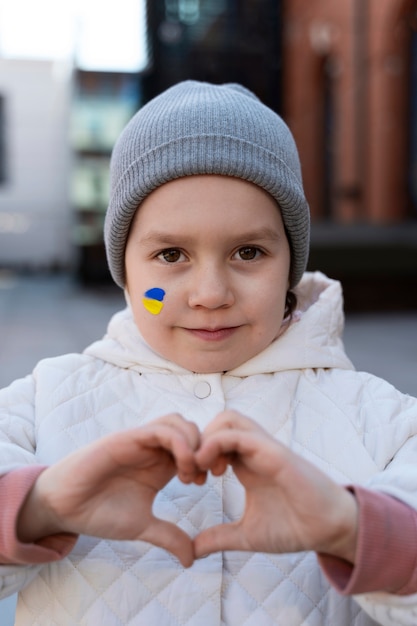 Free photo front view little kid with ukrainian flag paint