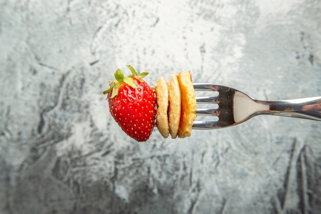 포크와 가벼운 표면 케이크 과일 디저트에 딸기와 전면보기 작은 팬케이크