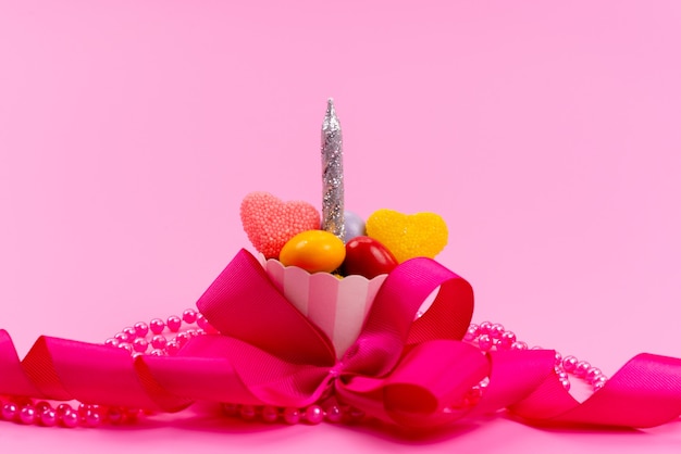 사탕과 분홍색으로 디자인 된 은색 촛불이있는 전면보기 작은 선물, 분홍색에 고립 된 활, 현재 생일 축하