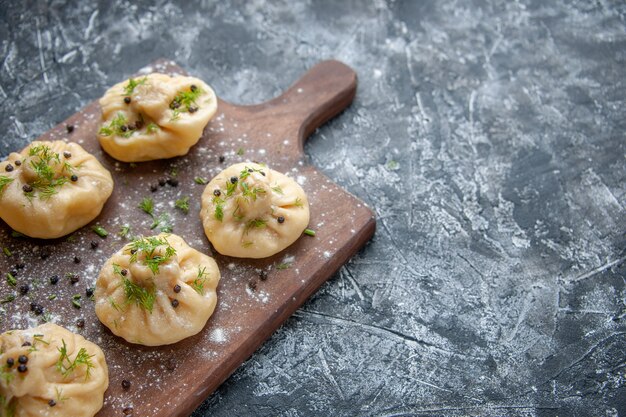 Front view little raw dumplings on light gray surface dough meat cuisine meal cooking dish cake dinner