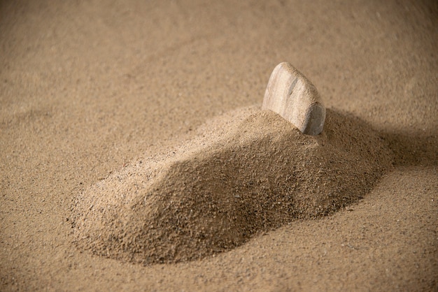 Front view of little stone grave on moon sand