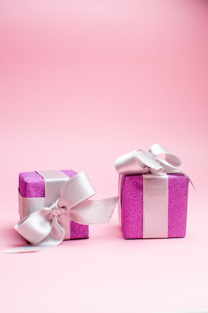 Вид спереди маленькие рождественские подарки на розовом рождественском цветном подарке фото новогодний праздник