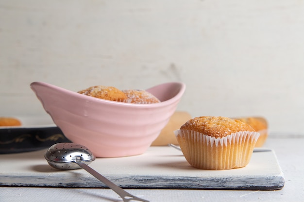 Free photo front view of little yummy cakes with sugar powder on the white surface