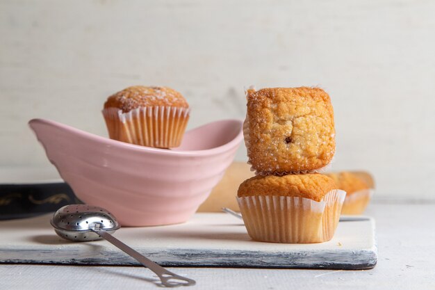 Front view of little yummy cakes with sugar powder on the white surface