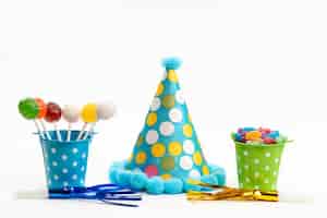 Foto gratuita una vista frontale lecca-lecca e caramelle colorate all'interno di cestini insieme al tappo di compleanno su bianco, colore zucchero candito