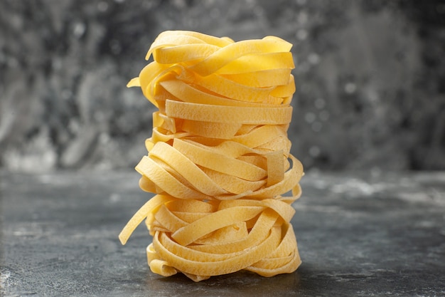 Foto gratuita vista frontale pezzi di pasta lunga arrotolati su sfondo grigio pasto di pasta cibo pasta oscurità cucina