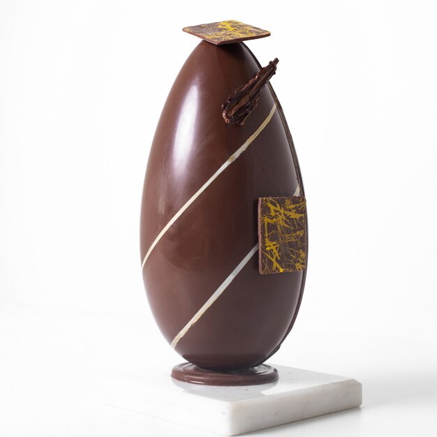 Front view long egg chocolate designed with white lines on the white desk