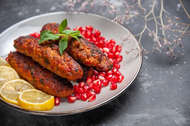 Front view long meat cutlets with lemon and pomegranates