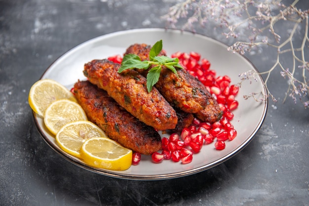 Front view long meat cutlets with lemon and pomegranates