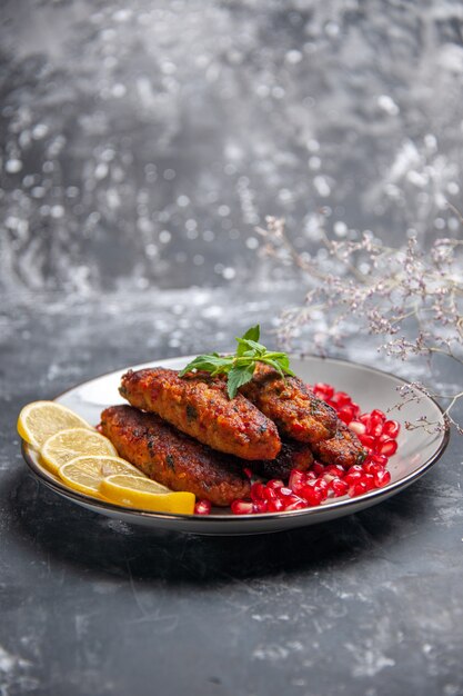 Front view long meat cutlets with lemon and pomegranates