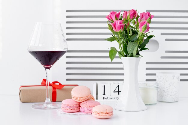 Front view of macarons with wine glass and vase of roses