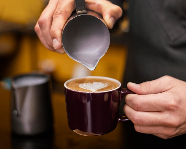 Front view of male barista pouring coffee in cup
