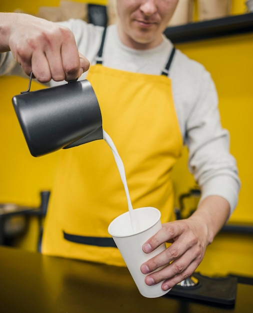 Foto gratuita vista frontale del latte di versamento di barista maschio in tazza