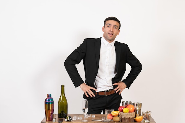 Front view male bartender in classic suit standing and posing on white wall club male night bar drink alcohol