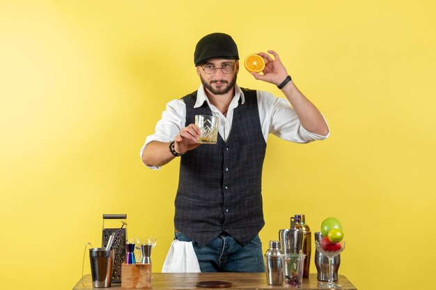 Front view male bartender in front of bar desk making drink on yellow wall bar alcohol night youth drink club