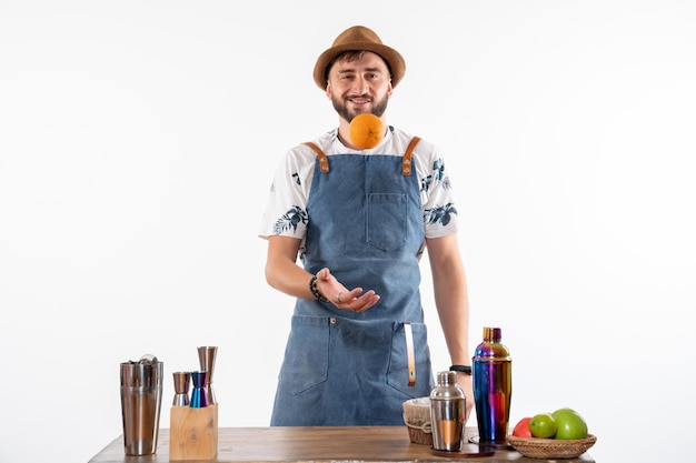 Barista maschio vista frontale davanti al bancone del bar che gioca con la frutta sul pavimento bianco bar alcol lavoro notturno club di bevande alla frutta