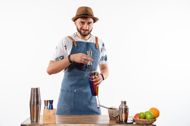 Front view male bartender in front of bar desk preparing a drink in shaker on white desk bar alcohol job fruit drink club night