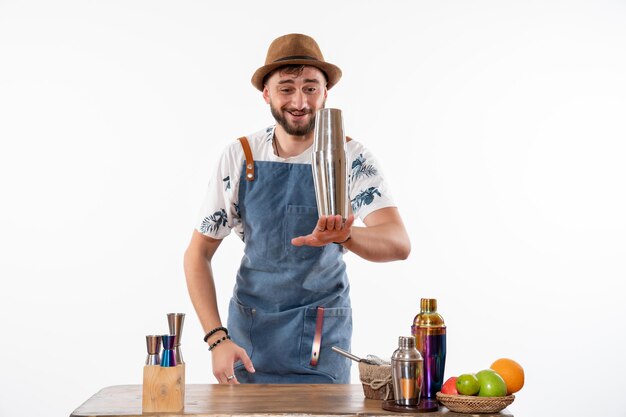 Front view male bartender in front of bar desk preparing a drink on a white wall bar alcohol job fruit club night drink