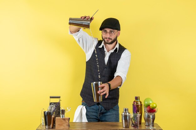 노란색 벽 바 알코올 나이트 청소년 음료 클럽에서 셰이커가 있는 탁자 앞에 있는 남성 바텐더