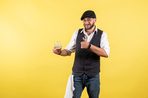 Front view male bartender holding glass on yellow wall drink alcohol job club bar night male