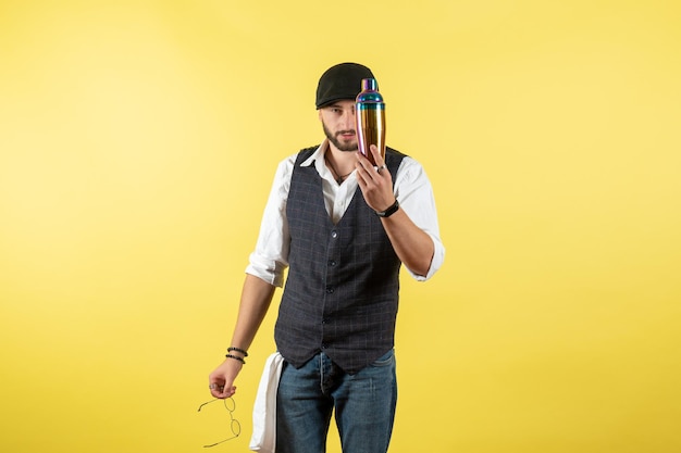 Front view male bartender holding shaker on yellow wall night model job drink work club male