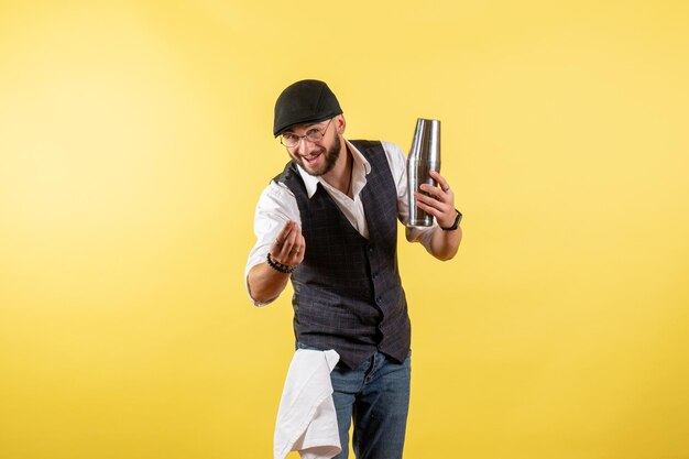 Front view male bartender holding silver drink shaker on the yellow wall drink alcohol job club bar night male