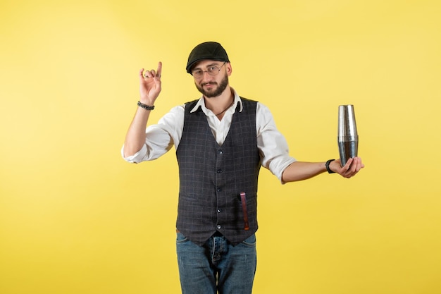 Front view male bartender holding silver shaker on yellow wall drink job club alcohol male bar night