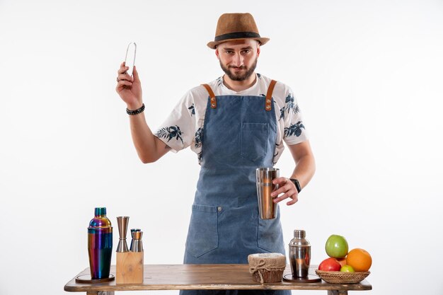 Front view male bartender making a drink in shaker on white wall bar alcohol club night drink job