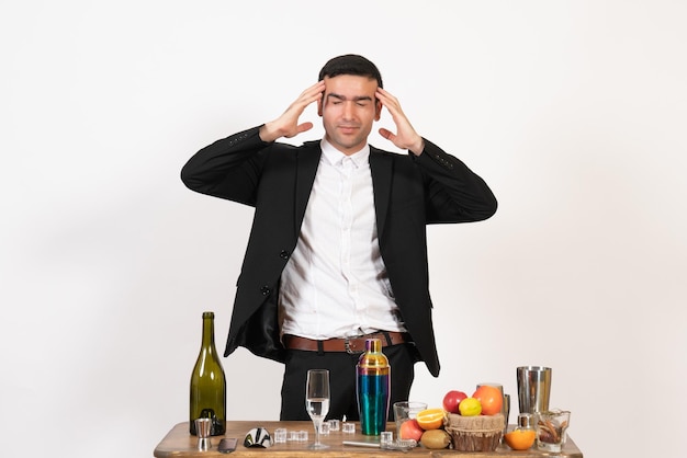 Front view male bartender standing in front of table with drinks posing on white floor night male bar alcohol drink club