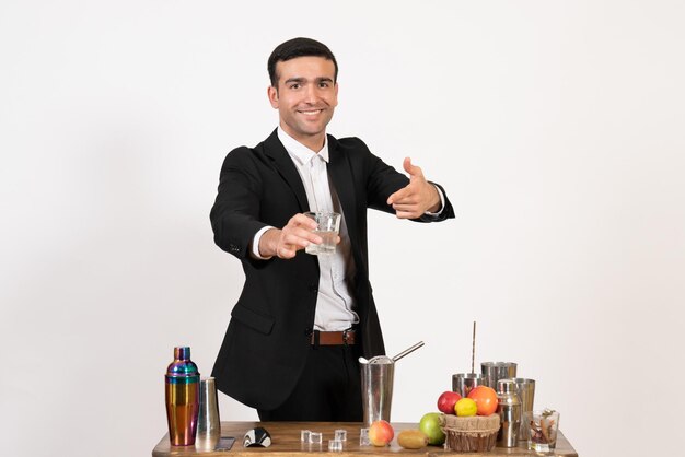 Front view male bartender in suit working with shakers and making drink on white wall night drinks bar club male dance