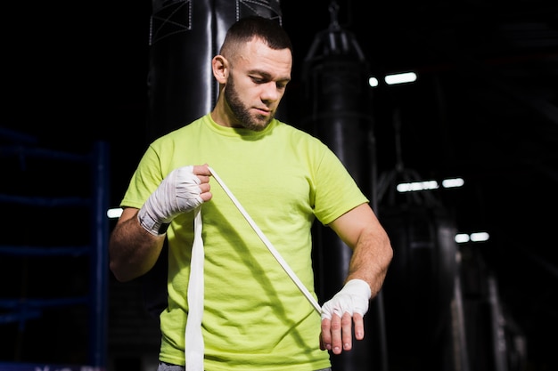 Free photo front view of male boxer putting on protection for hands