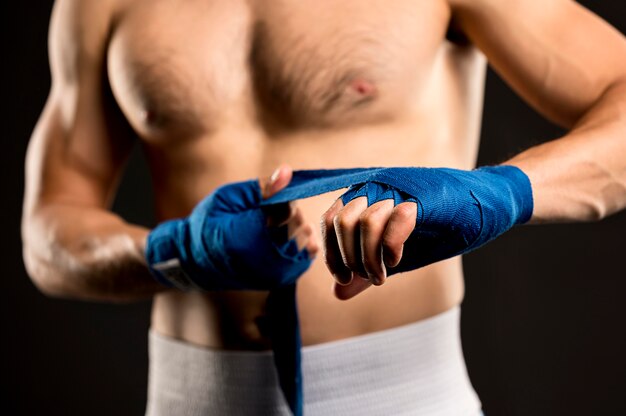 Front view of male boxer putting on protection for hands