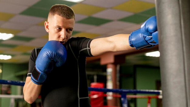 Front view of male boxer with gloves training at the ring