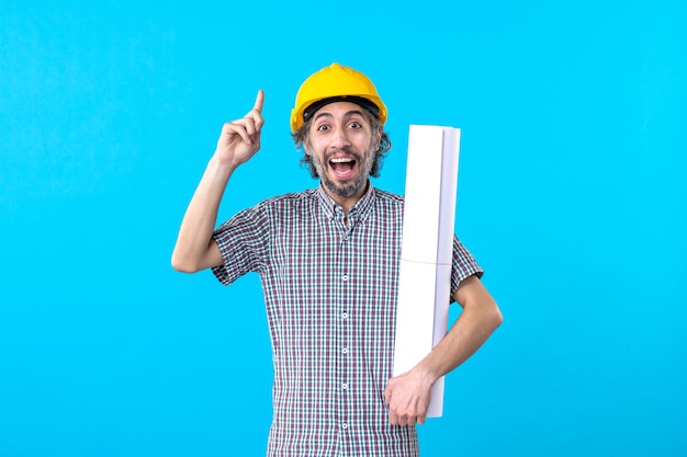 Front view male builder in helmet holding plan on the blue