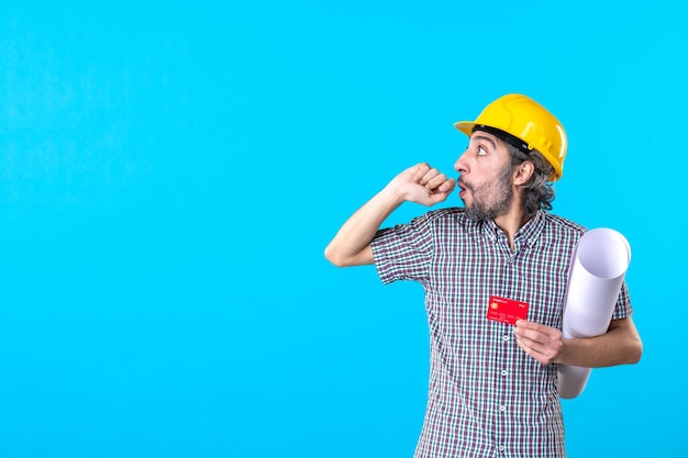 Free photo front view male builder holding plan and bank card on blue background money design constructor architecture building job colors