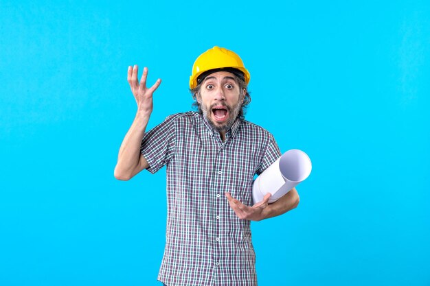 Front view male builder holding plan on blue background architecture skyscraper constructor engineer job buildings color