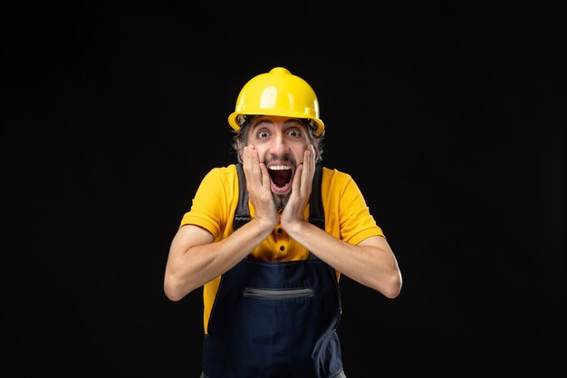 Front view male builder in uniform on black wall