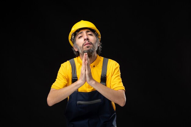 Front view male builder in uniform on black wall