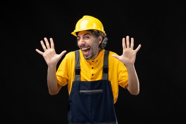 Front view of male builder in uniform on black wall