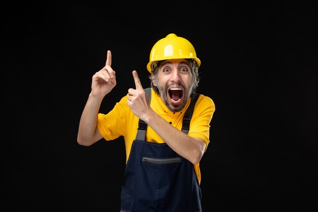 Front view of male builder in uniform on the black wall