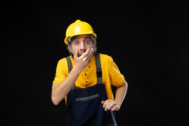 Front view male builder in uniform on black wall