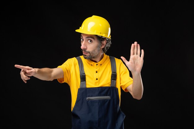 Front view male builder in uniform on black wall