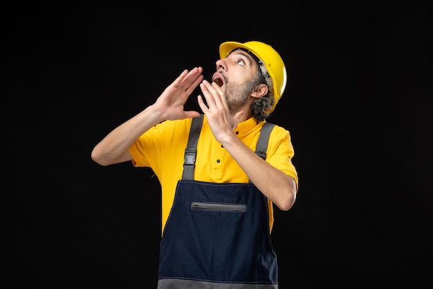 Foto gratuita costruttore maschio vista frontale in uniforme sul muro nero